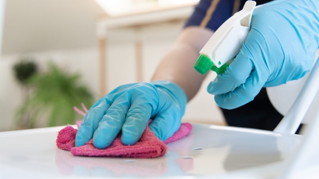 Deep cleaning service disinfecting a countertop with spray cleaner and microfiber cloth for a spotless home.